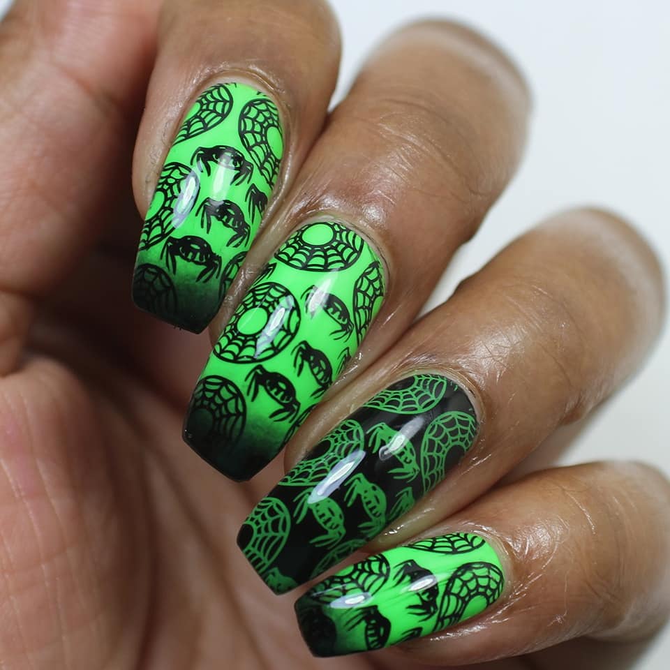 green nails with black spiders in the shape of doughnuts 
